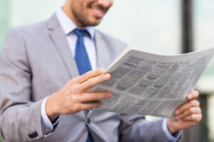 professional male in business suit reading newspaper